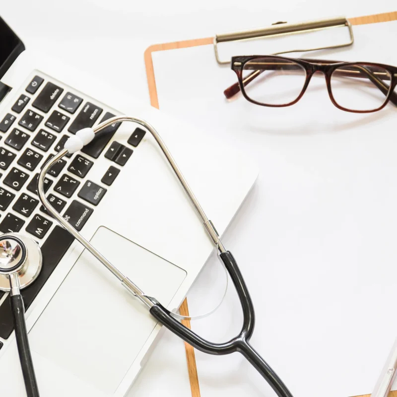 overhead-view-stethoscope-open-laptop-with-clipboard-eyeglasses-white-background_11zon